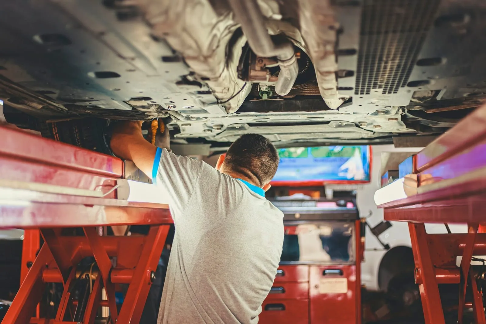 Mechaniker prüft den Unterboden eines Fahrzeugs auf der Hebebühne beim Vorab-Check vor der Hauptuntersuchung